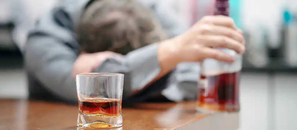 Alkohol kalkulátor véralkohol szint férfi alkoholos üveg mellett asztalnál